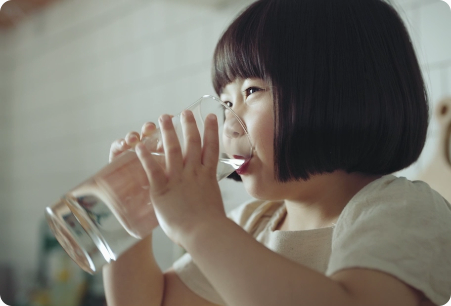 단발머리 여자아이 한명이 투명 유리컵에 담긴 물을 마시고 있습니다.